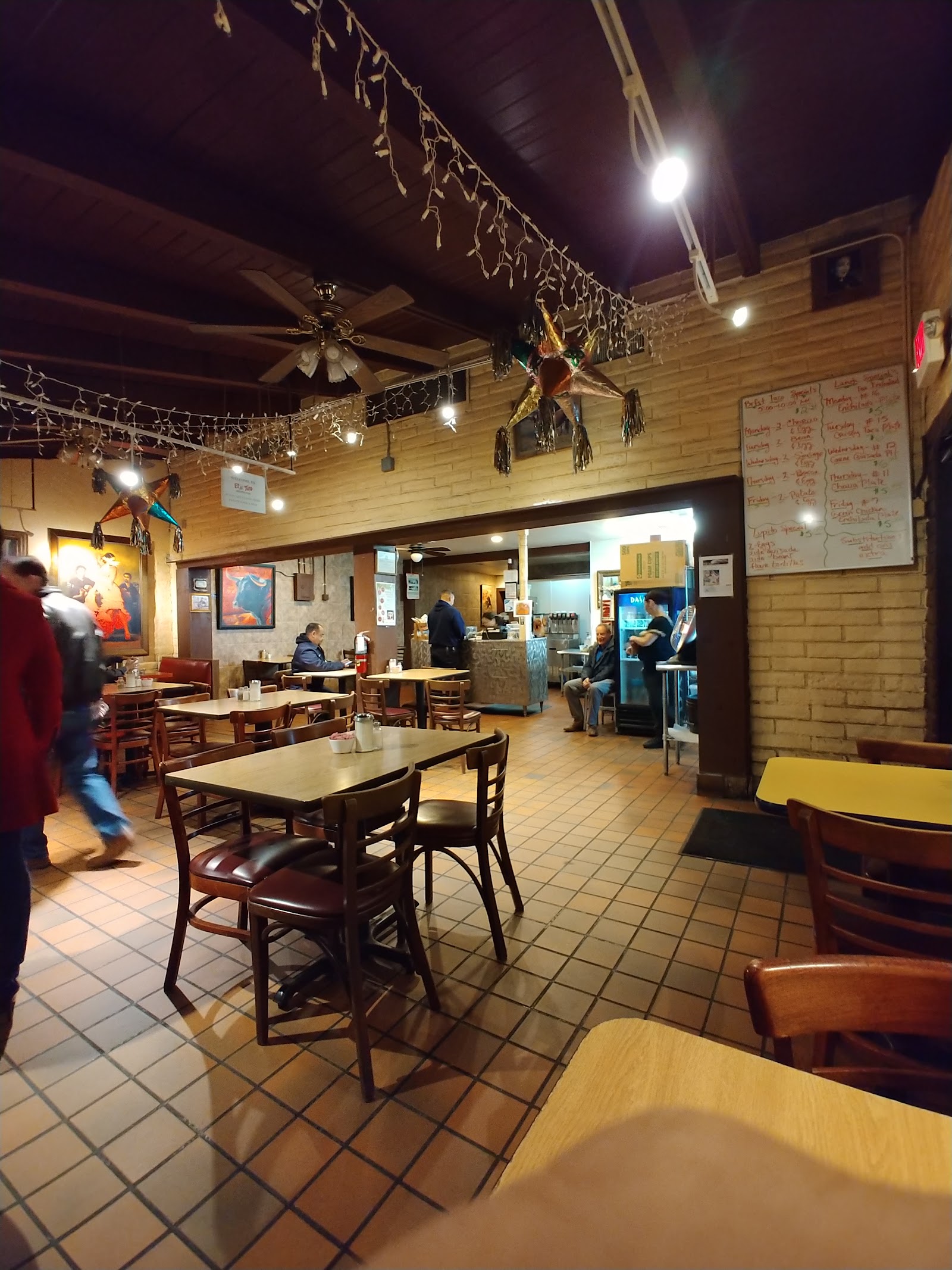Cozy dining room inside El Toro Mexican Food with string lights and piΓ±atas
