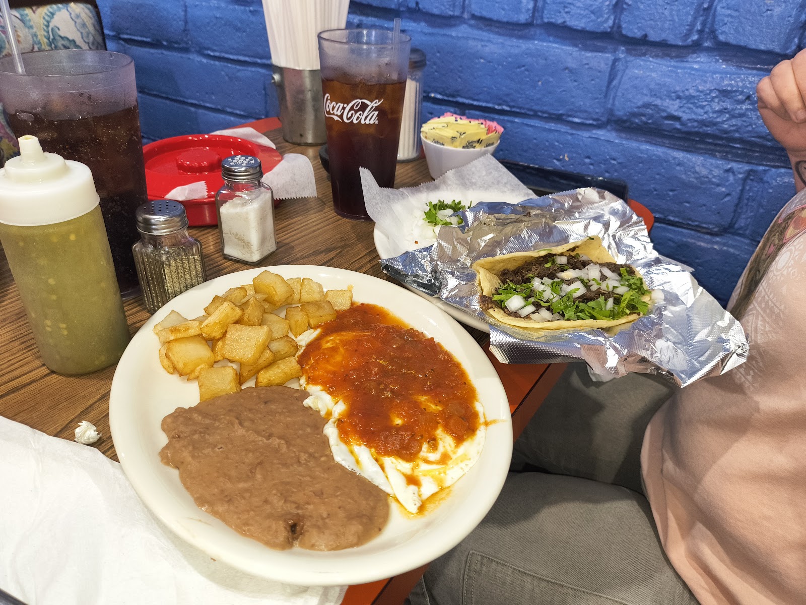 Breakfast plate with fried eggs, refried beans, crispy papas, and a beef taco